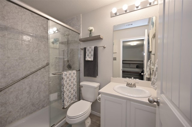 full bathroom with vanity, a shower stall, toilet, and visible vents