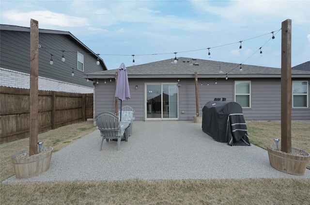 back of house with a patio area, a shingled roof, and fence