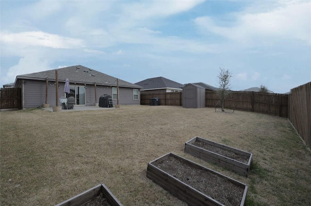 view of yard with an outbuilding, a vegetable garden, a fenced backyard, a storage shed, and a patio area