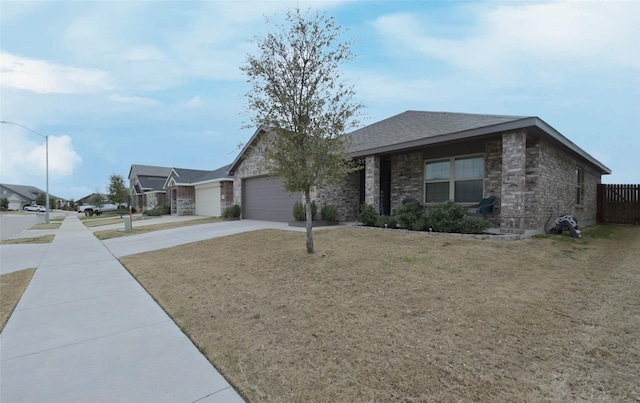 ranch-style house with a shingled roof, fence, concrete driveway, a front yard, and a garage