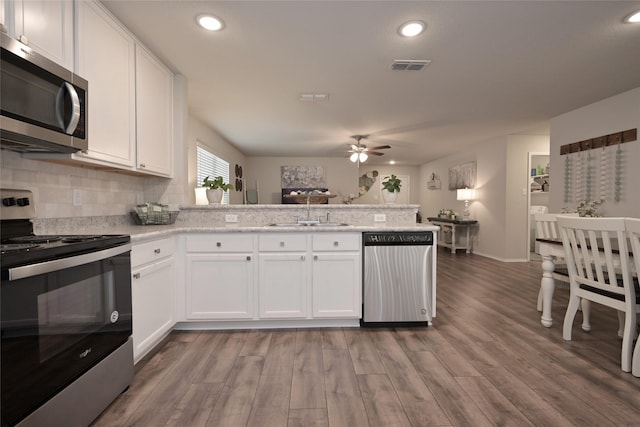 kitchen with visible vents, a peninsula, ceiling fan, a sink, and stainless steel appliances