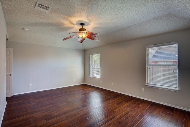 spare room featuring baseboards, dark wood-style floors, ceiling fan, and visible vents