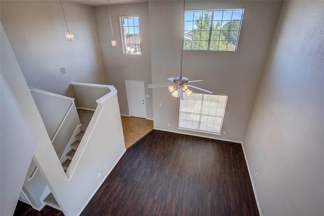foyer featuring stairs, a ceiling fan, a high ceiling, wood finished floors, and baseboards