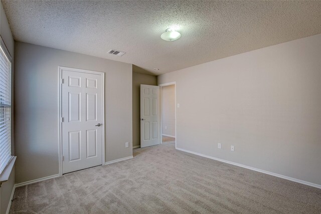 unfurnished bedroom featuring light carpet, baseboards, visible vents, and a textured ceiling