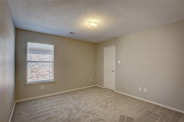 carpeted empty room featuring baseboards, a textured ceiling, and visible vents