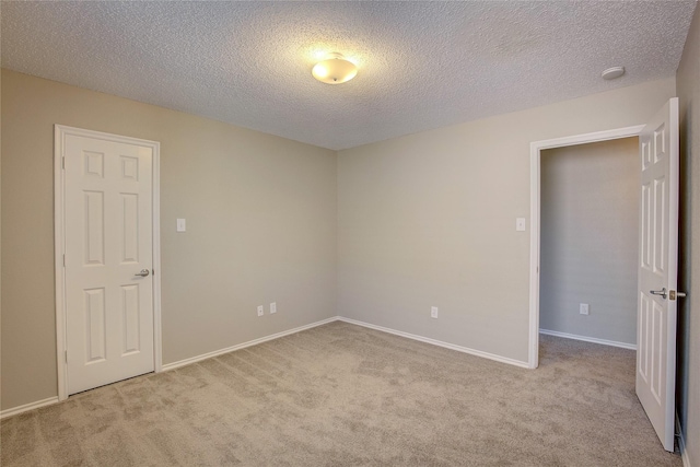 carpeted empty room featuring baseboards and a textured ceiling