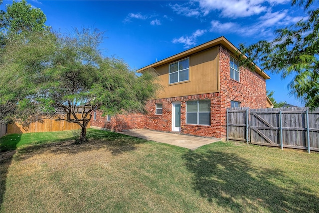 rear view of house with a fenced backyard, a patio, brick siding, and a yard