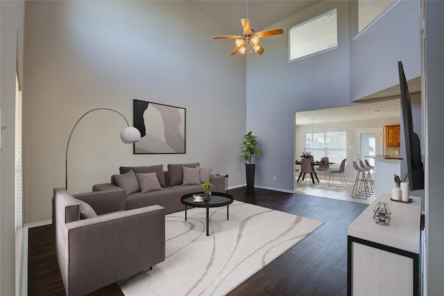living room with baseboards, a towering ceiling, dark wood-type flooring, and a ceiling fan