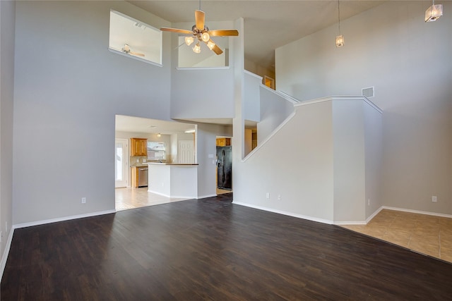 unfurnished living room featuring a ceiling fan, visible vents, baseboards, and wood finished floors