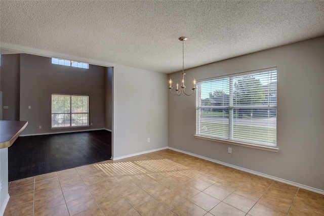 tiled spare room featuring baseboards, a chandelier, and a wealth of natural light