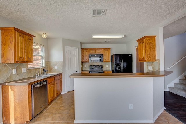 kitchen featuring light tile patterned flooring, a sink, a peninsula, visible vents, and black appliances