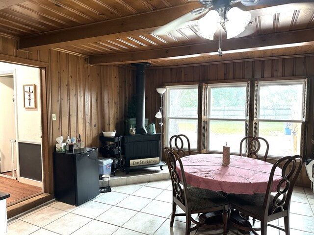 1704 S Houston St, Kaufman, TX 75142 - dining area featuring light tile patterned flooring, a wood stove, wooden walls, wood ceiling with exposed beams, and a ceiling fan