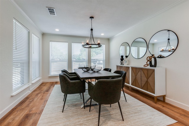 dining room with ornamental molding, visible vents, a chandelier, light wood finished floors, and baseboards