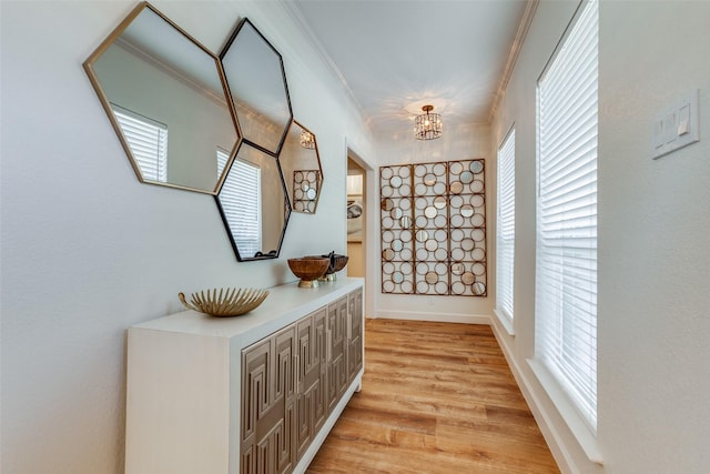hall featuring a chandelier, light wood-type flooring, ornamental molding, and washer / dryer