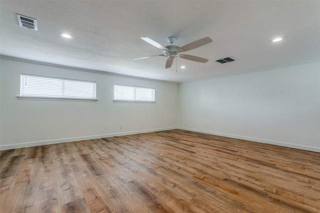 spare room featuring ornamental molding, visible vents, ceiling fan, and wood finished floors