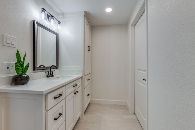 bathroom with baseboards, recessed lighting, and vanity