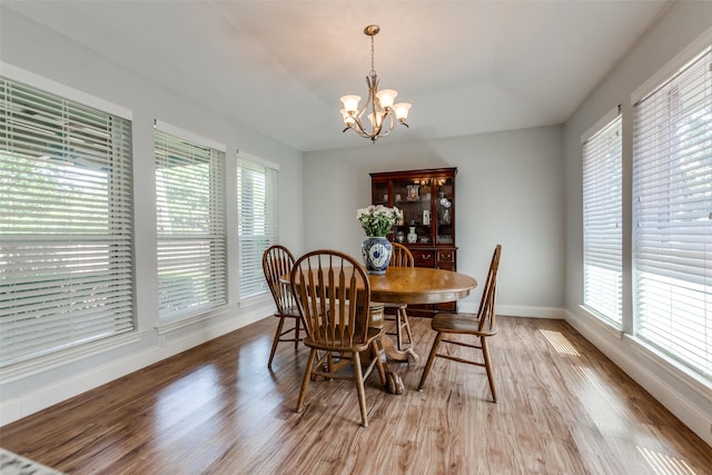 dining room featuring light wood-style flooring, a healthy amount of sunlight, baseboards, and a notable chandelier