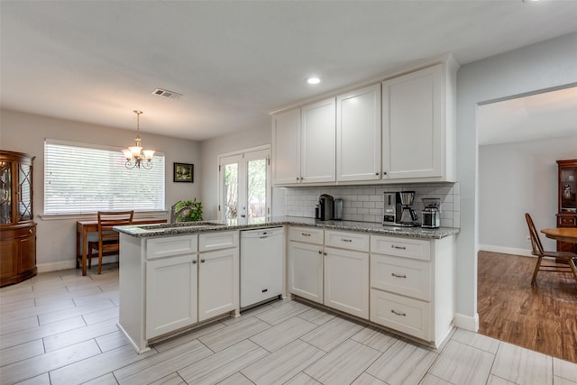 kitchen featuring tasteful backsplash, baseboards, a peninsula, white cabinetry, and white dishwasher