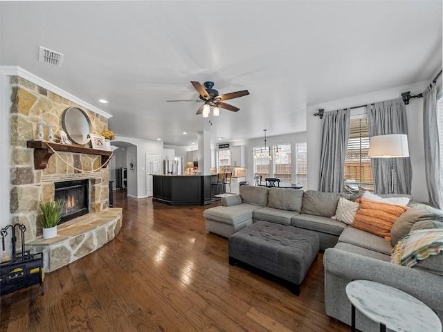 7601 Glenwood Springs Ln, Mckinney, TX 75070 - living room featuring a fireplace, visible vents, dark wood finished floors, arched walkways, and ceiling fan