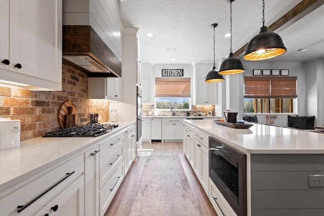 kitchen with backsplash, a center island, light stone counters, light wood-style flooring, and appliances with stainless steel finishes