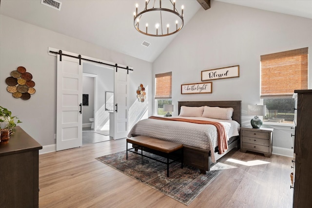 bedroom featuring visible vents, high vaulted ceiling, a notable chandelier, wood finished floors, and a barn door