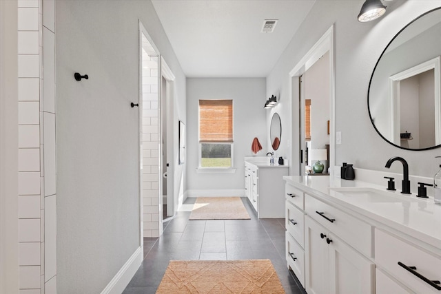 bathroom featuring visible vents, two vanities, baseboards, and a sink