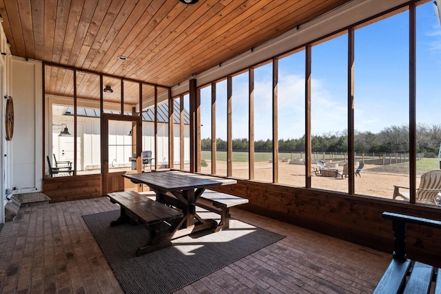 unfurnished sunroom featuring outdoor dining space, wood ceiling, brick floor, and a wealth of natural light