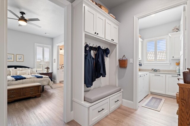 mudroom with plenty of natural light, independent washer and dryer, a ceiling fan, and light wood-style floors