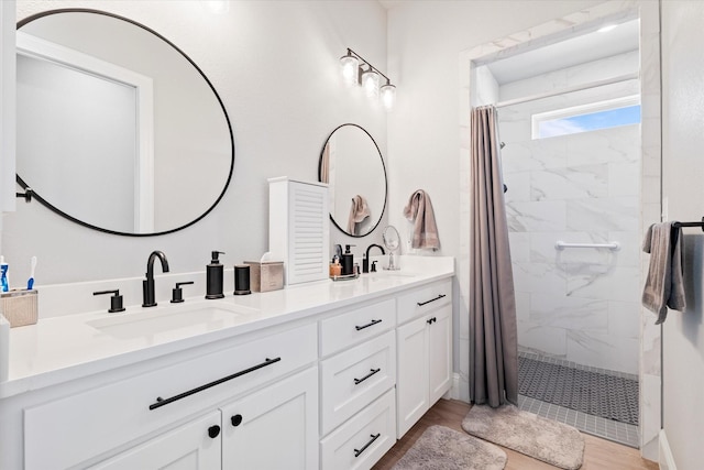 bathroom with double vanity, tiled shower, and a sink