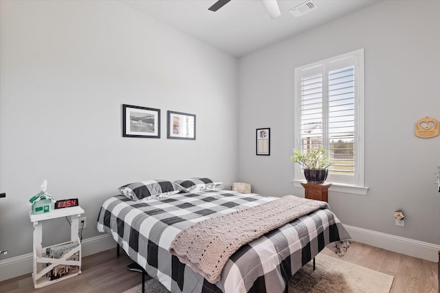 bedroom featuring visible vents, a ceiling fan, baseboards, and wood finished floors