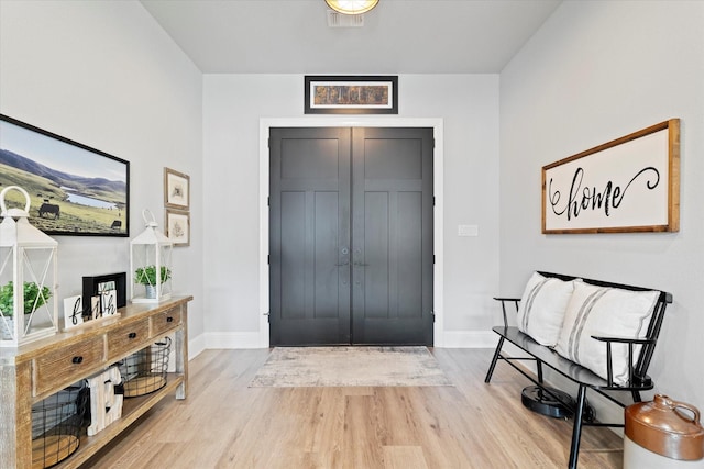 foyer entrance with visible vents, baseboards, and wood finished floors