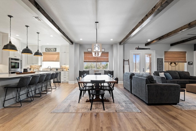 dining area featuring light wood-type flooring, visible vents, beam ceiling, and baseboards