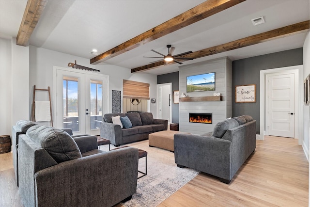 living area with visible vents, light wood-style flooring, a fireplace, french doors, and a ceiling fan