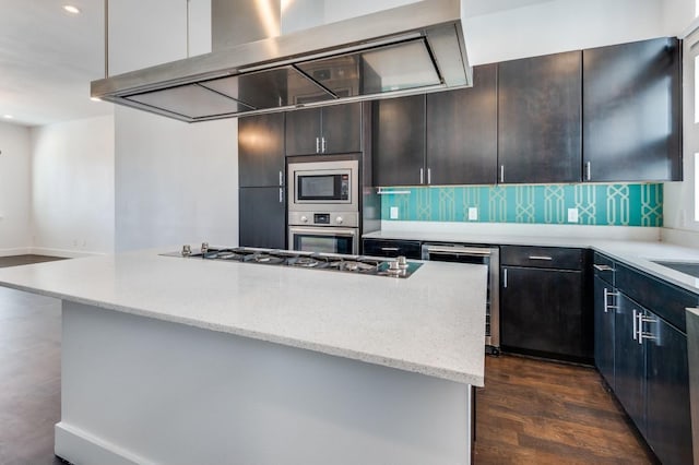 4609 Steel St, Dallas, TX 75219 - kitchen with light stone counters, decorative backsplash, dark wood-style floors, stainless steel appliances, and wall chimney exhaust hood