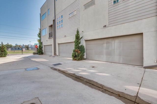 4609 Steel St, Dallas, TX 75219 - view of home's exterior with a garage, concrete driveway, stucco siding, and fence