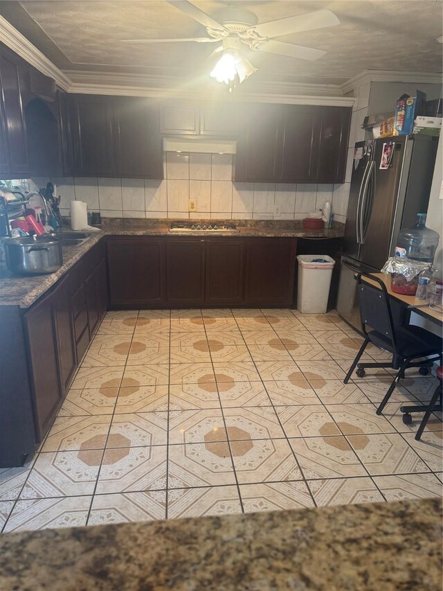 kitchen with crown molding, under cabinet range hood, decorative backsplash, light tile patterned flooring, and stainless steel appliances