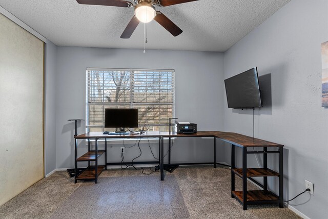 carpeted office space featuring a ceiling fan, baseboards, and a textured ceiling
