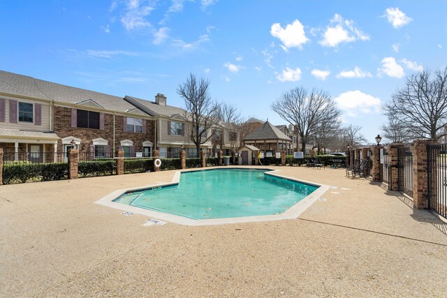 pool with a patio area, a residential view, and fence