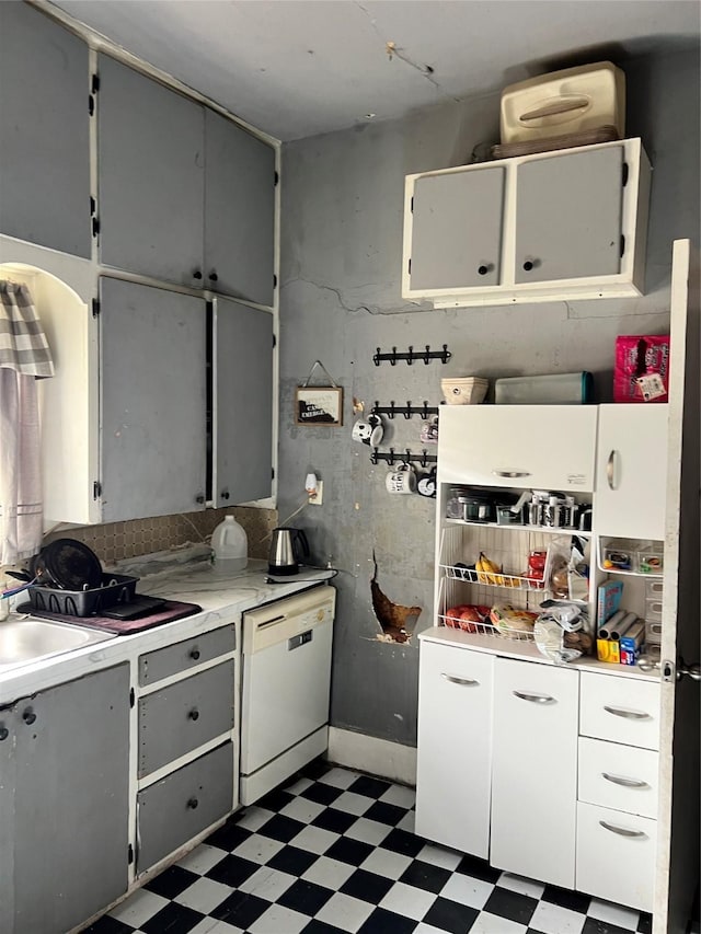 kitchen featuring light countertops, gray cabinets, light floors, and white dishwasher