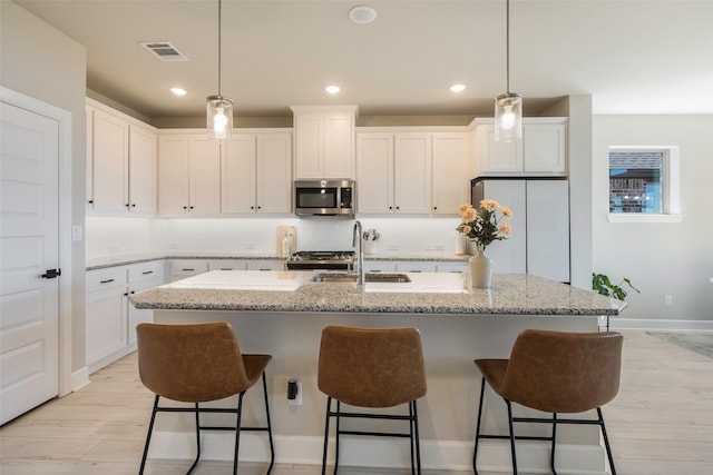kitchen featuring stainless steel appliances, visible vents, a sink, and white cabinetry