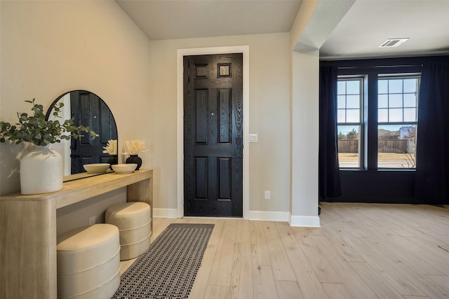 foyer featuring baseboards, wood finished floors, and visible vents