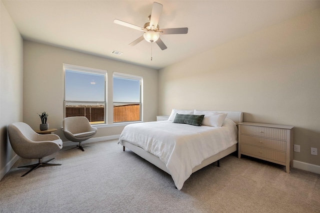 bedroom featuring baseboards, visible vents, light colored carpet, and ceiling fan