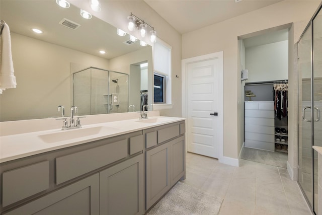 bathroom featuring a walk in closet, a sink, visible vents, and a stall shower