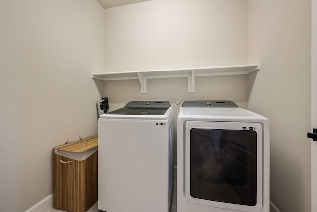 clothes washing area with washing machine and dryer, baseboards, and laundry area