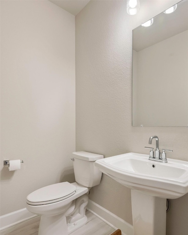 bathroom with toilet, wood finished floors, and baseboards