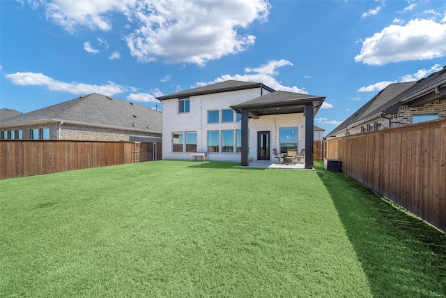 rear view of house with a fenced backyard, brick siding, a patio, and a lawn