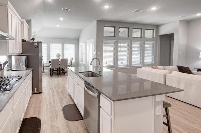 kitchen featuring visible vents, light wood-style flooring, a kitchen island with sink, a sink, and appliances with stainless steel finishes