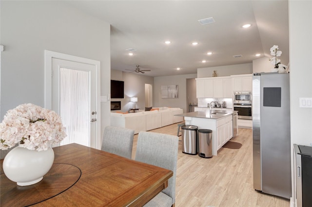 dining area featuring light wood finished floors, visible vents, wine cooler, recessed lighting, and a ceiling fan