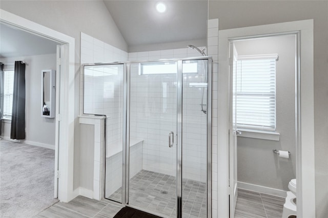 full bathroom featuring lofted ceiling, toilet, baseboards, and a shower stall