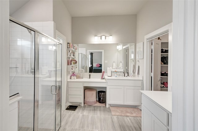 bathroom with vanity, a shower stall, a walk in closet, and connected bathroom